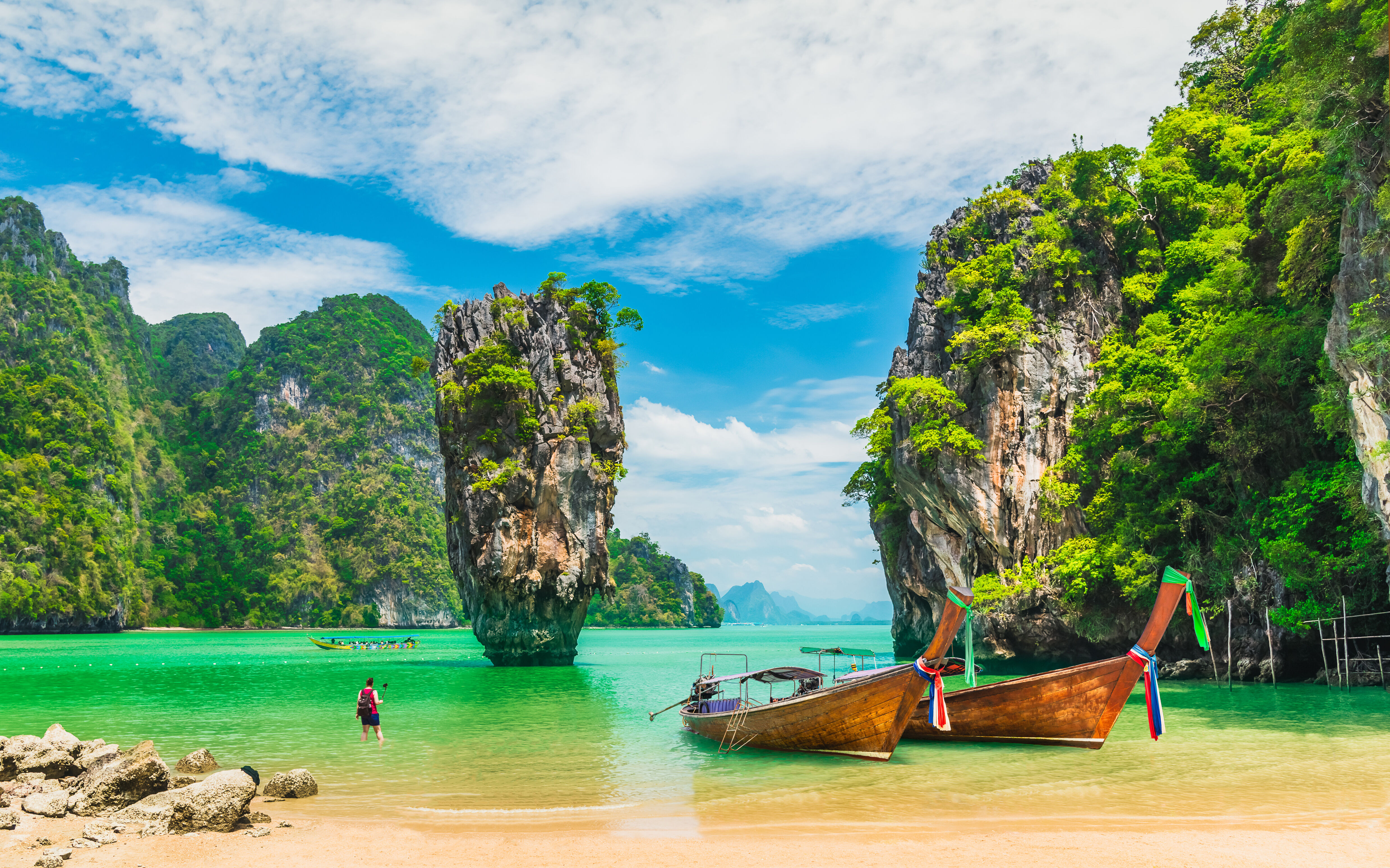 A photo of two boats in front of a beautiful Thailand backdrop.  