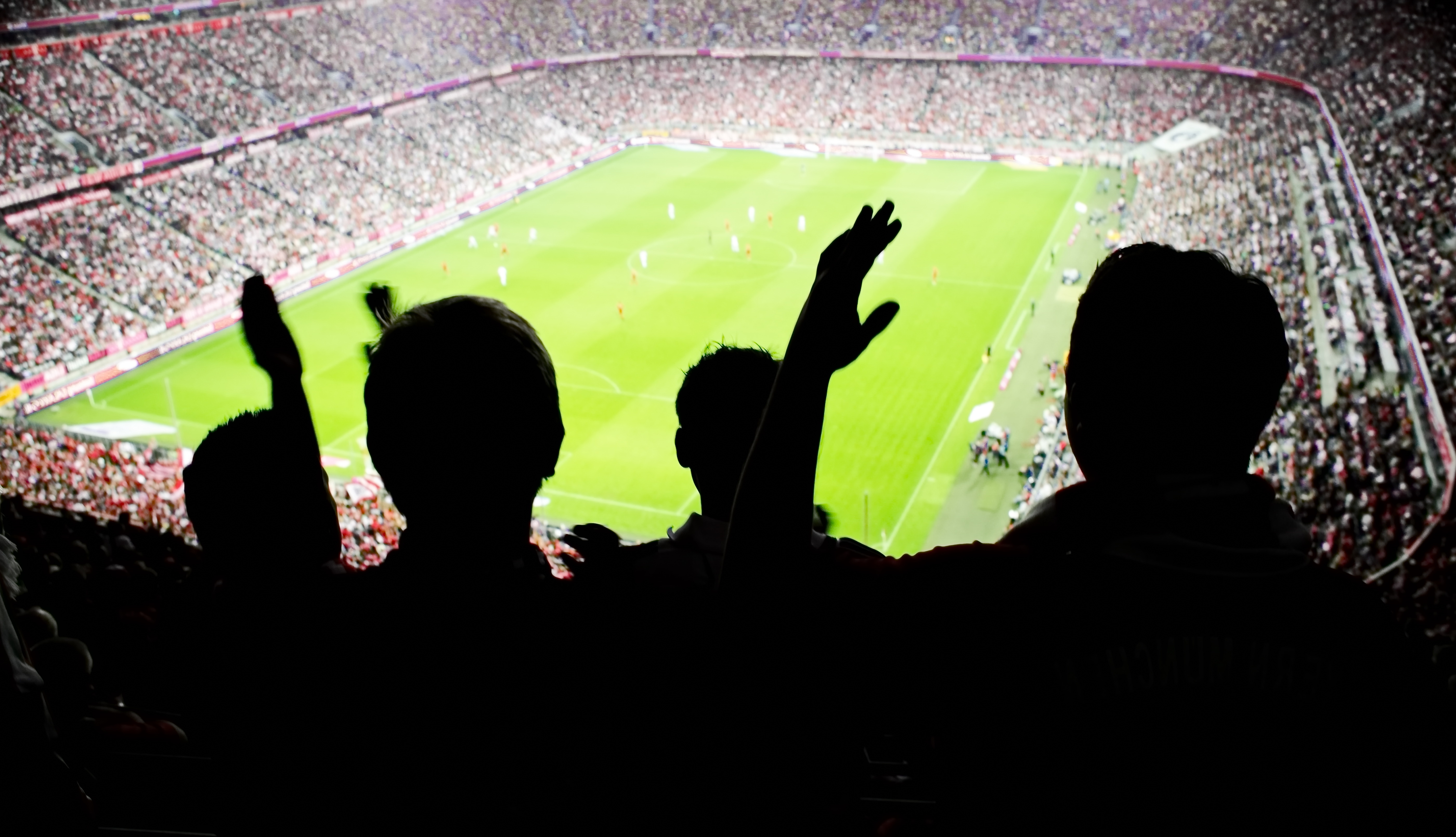 A silhouette of soccer fans watching a game. 