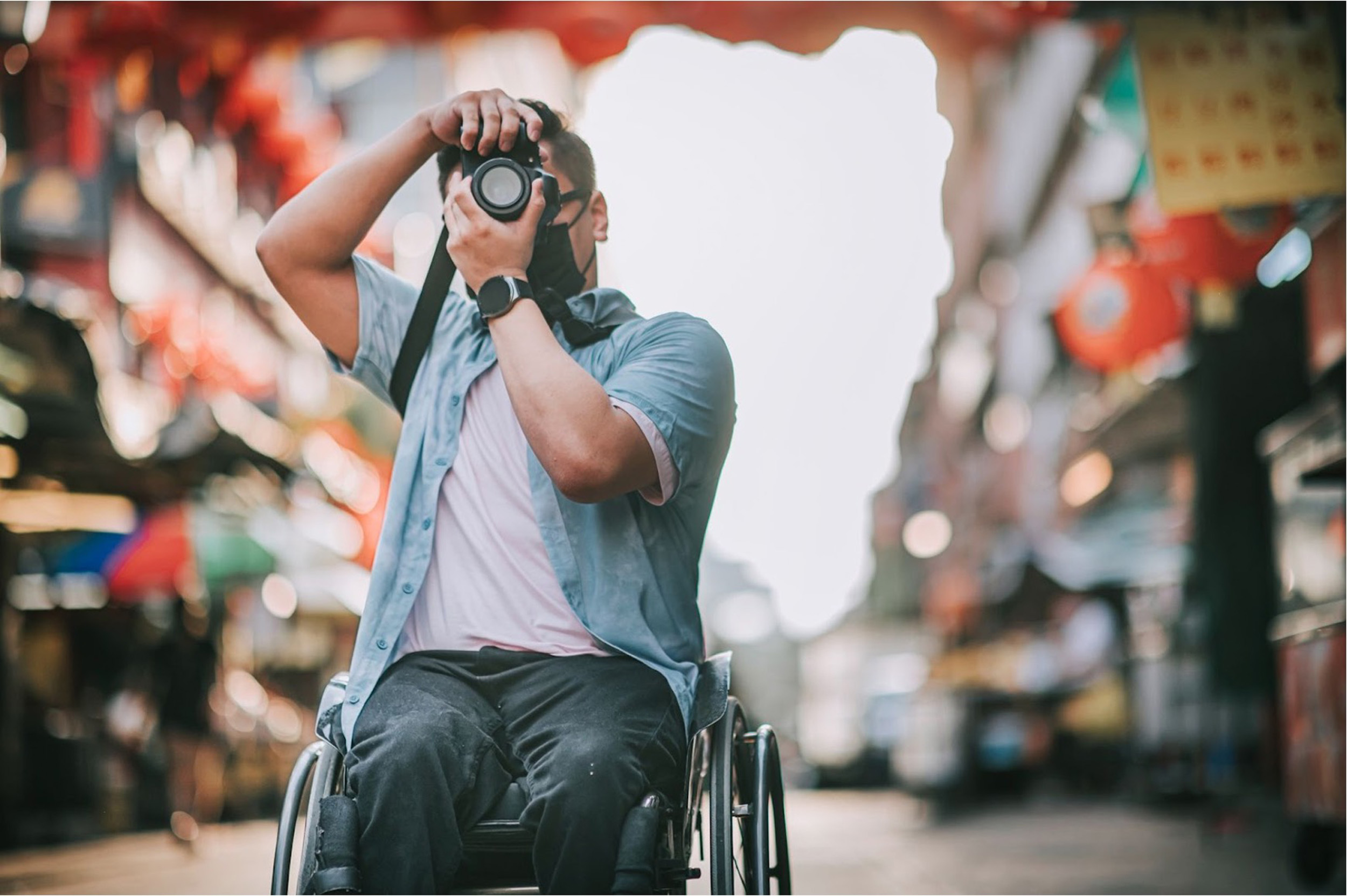 A photo of a man in a wheel chair aiming his camera up to take a photo. 
