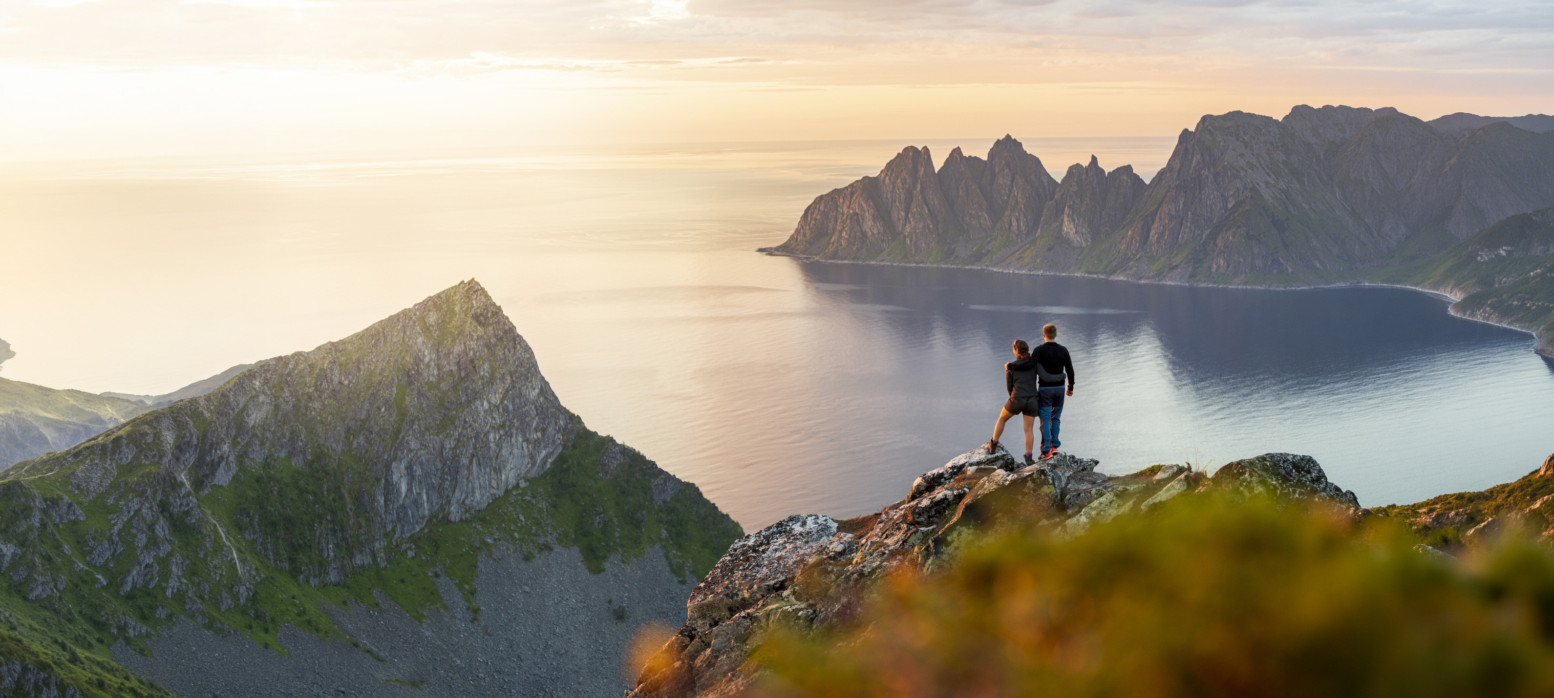 A photo of people on a mountain looking at the ocean. 