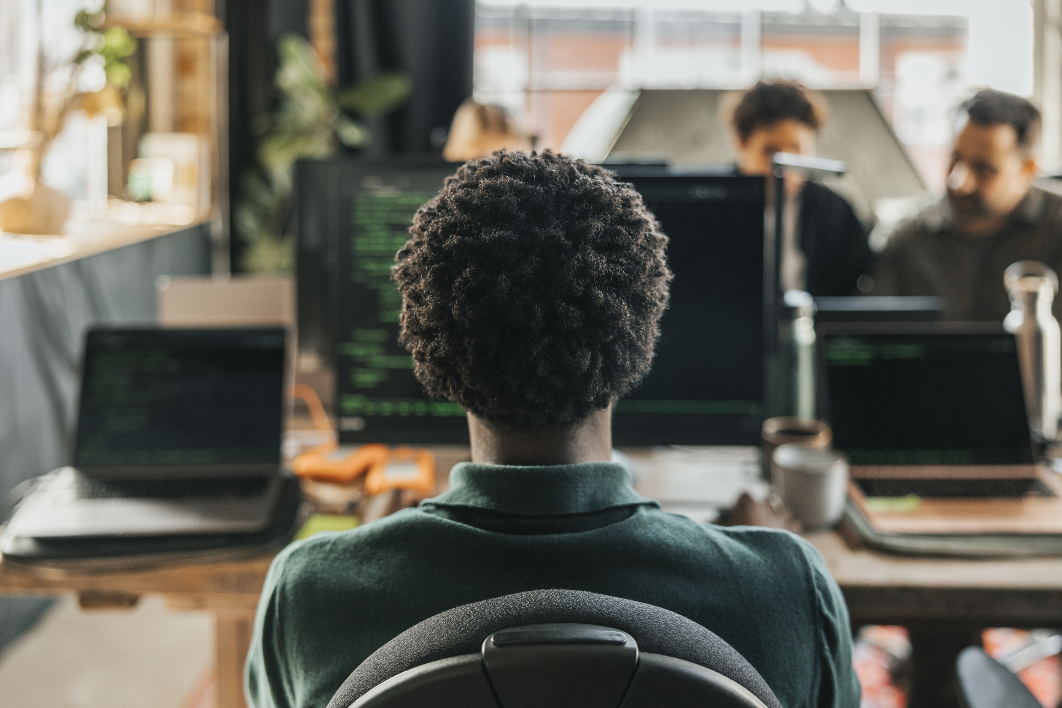 A photo of a curly-headed man sitting in front of a computer. 