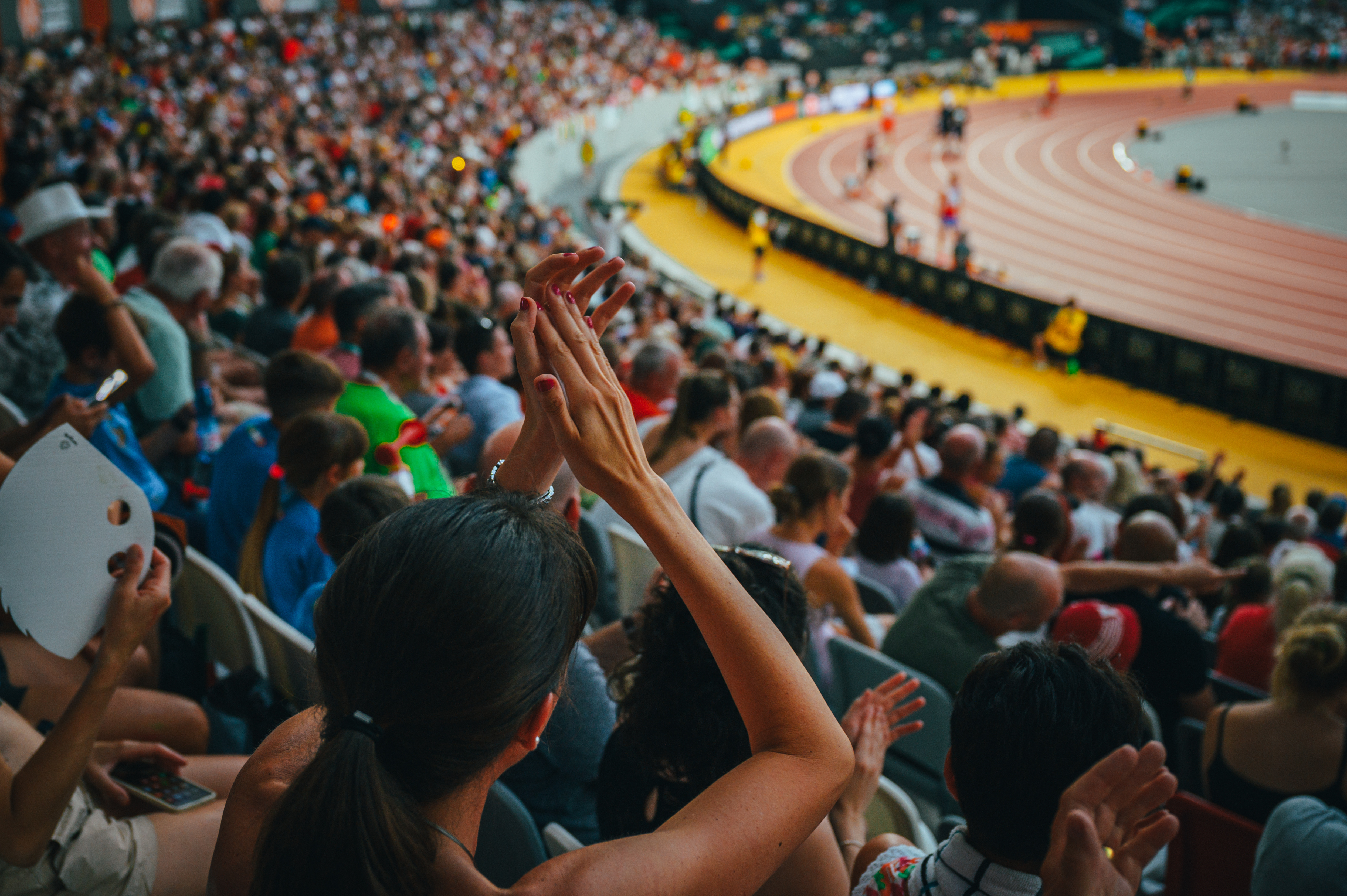 A woman applauding while watching a sporting event. 