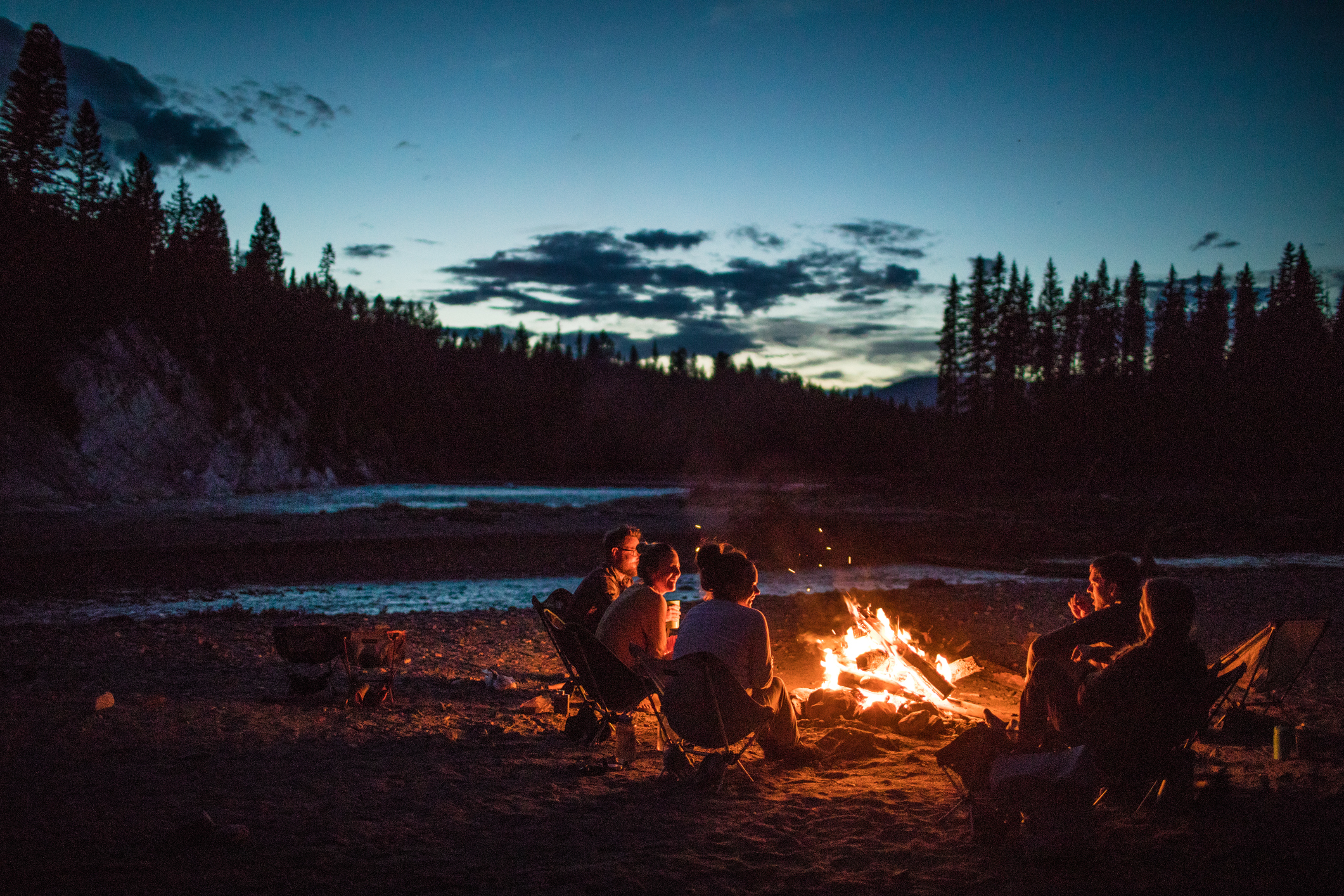 A group of people hanging out by a campfire. 