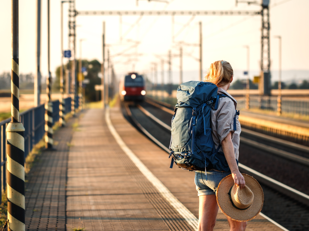 A photo of a traveler standing at railroad station, waiting for a train to arrive. 