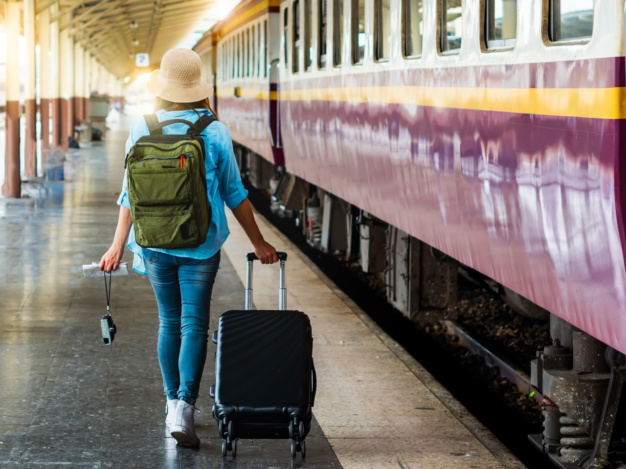 A photo of a woman with a suitcase taking a train. 
