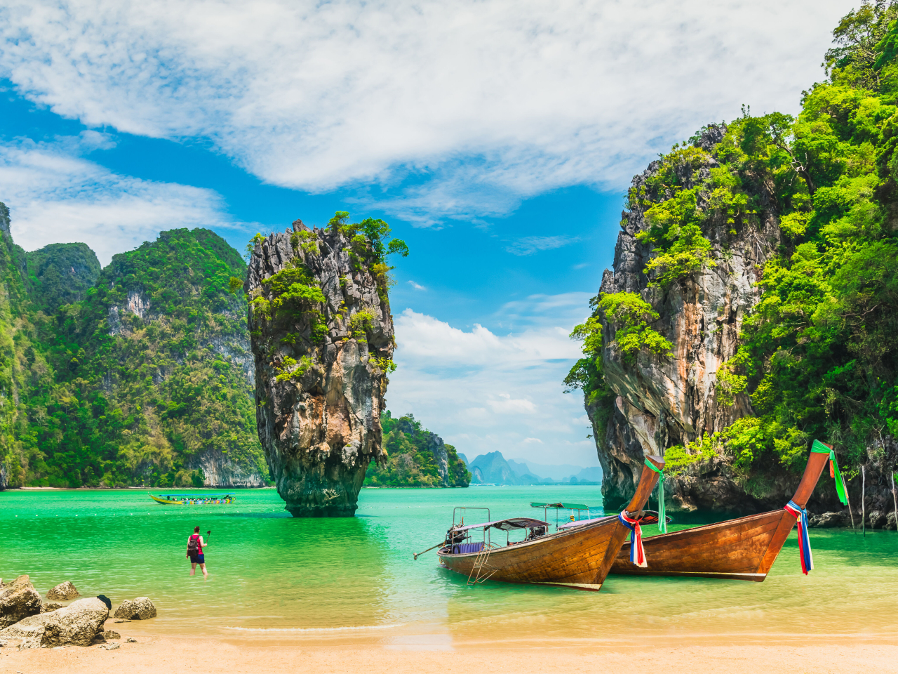 A photo of two boats in front of a beautiful Thailand backdrop.  