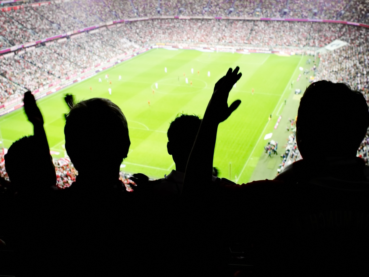 A silhouette of soccer fans watching a game. 
