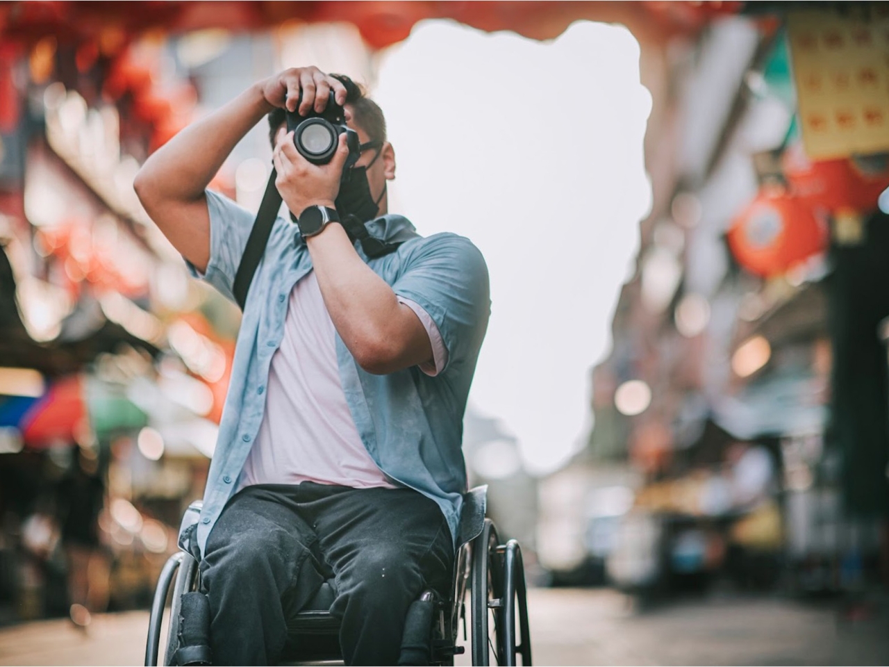 A photo of a man in a wheel chair aiming his camera up to take a photo. 