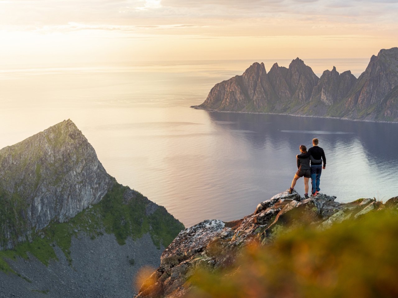 A photo of people on a mountain looking at the ocean. 
