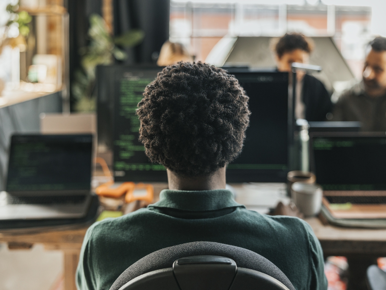 A photo of a curly-headed man sitting in front of a computer. 