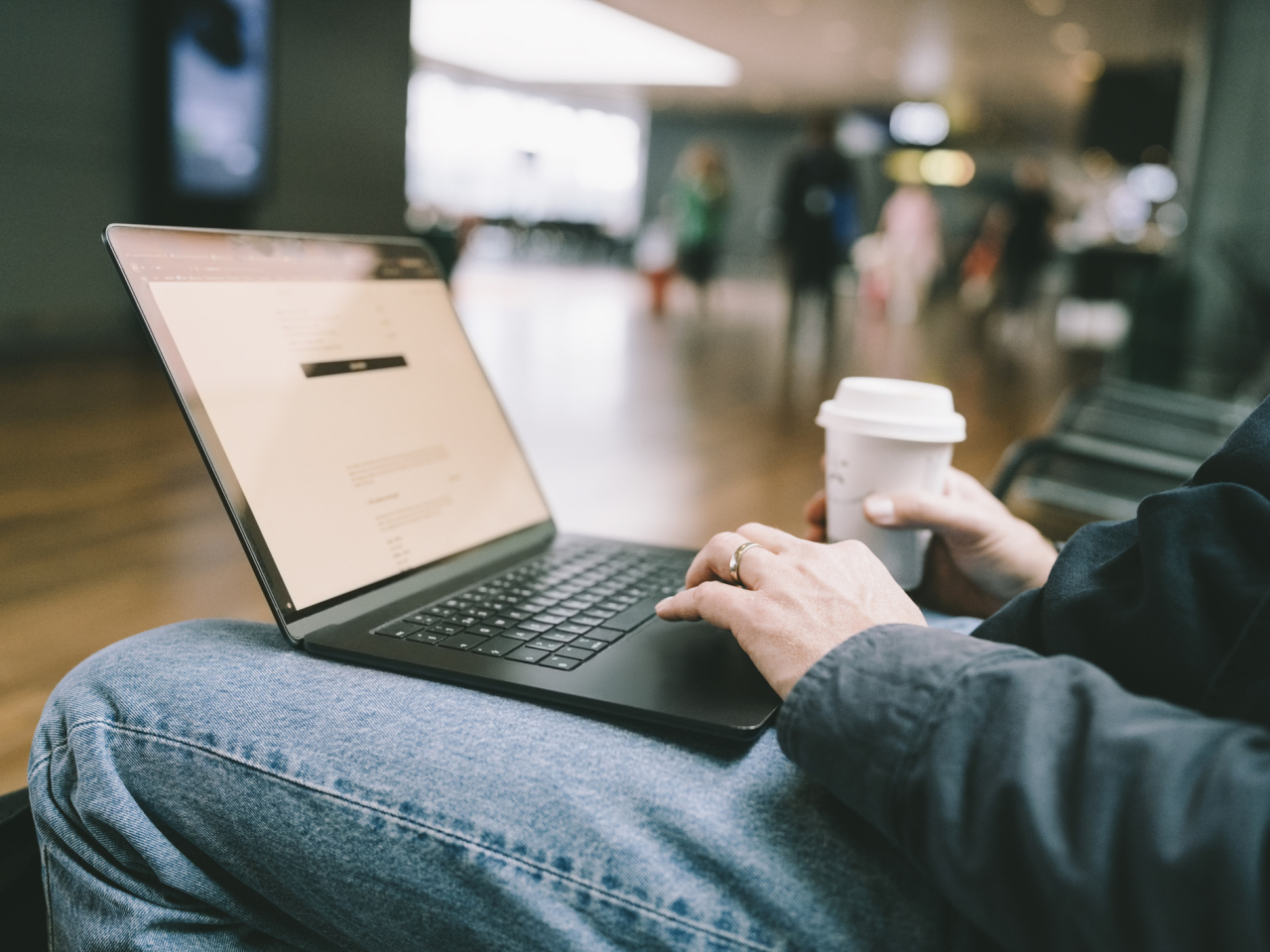 A man typing on his laptop while drinking coffee. 