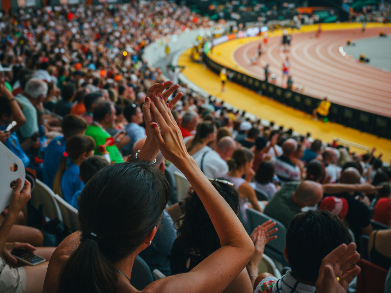 A woman applauding while watching a sporting event. 