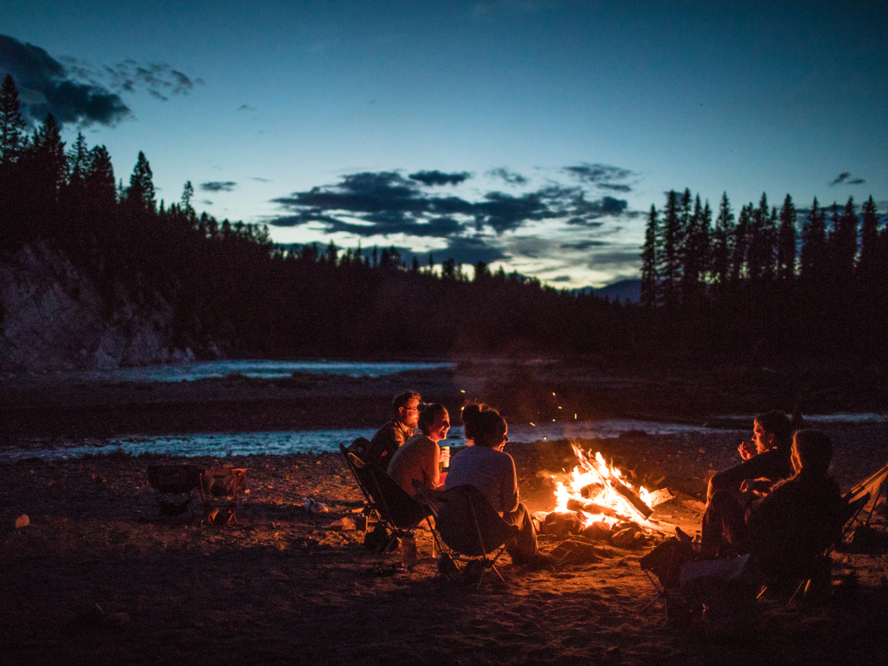 A group of people hanging out by a campfire. 