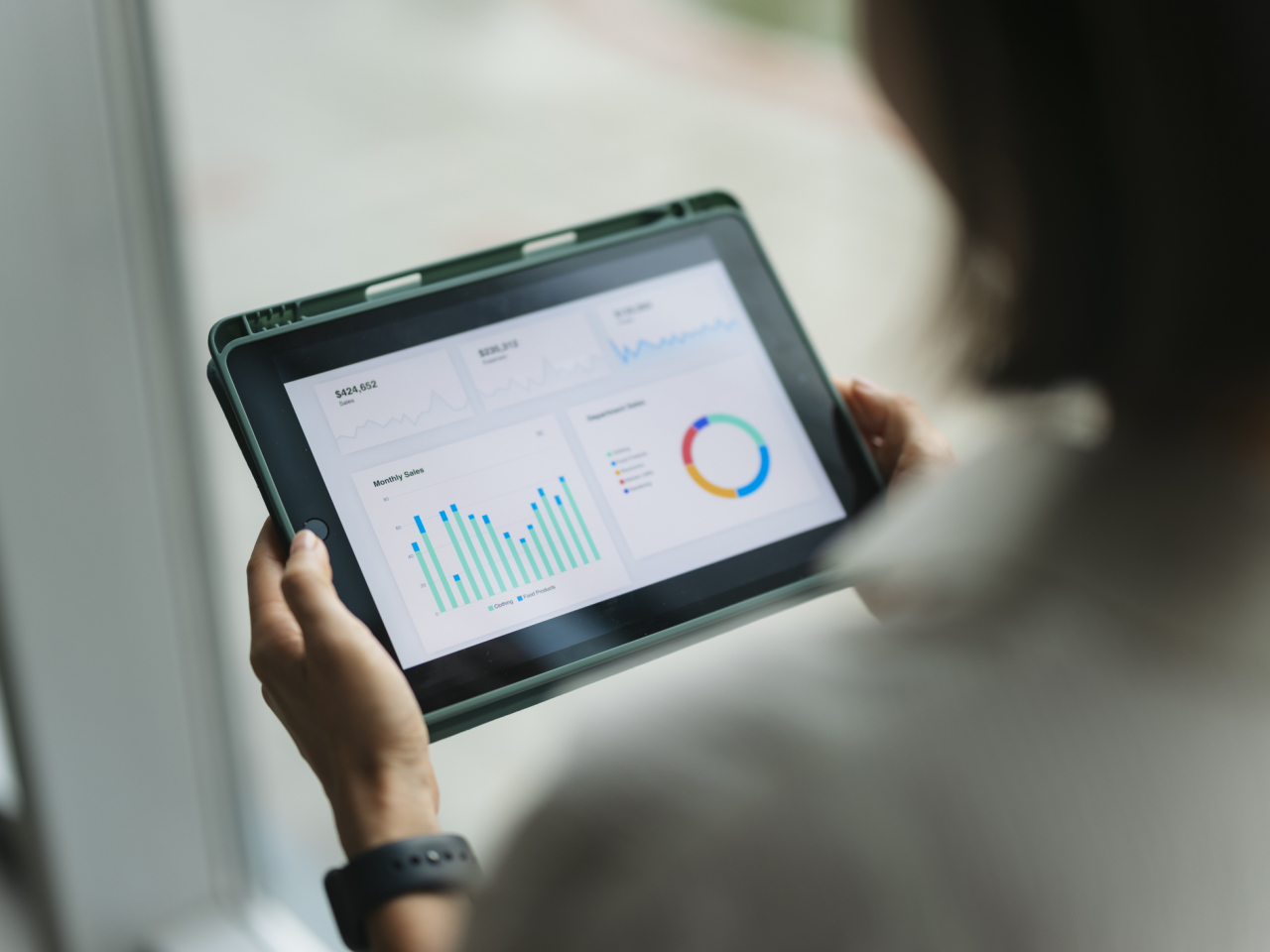 A photo of a person analyzing research on a tablet. 