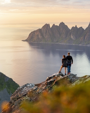 A photo of people on a mountain looking at the ocean. 