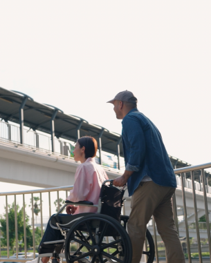 A man pushes a woman in a wheelchair. 