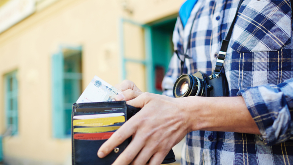 A closeup shot of a tourist taking money out of his wallet. 