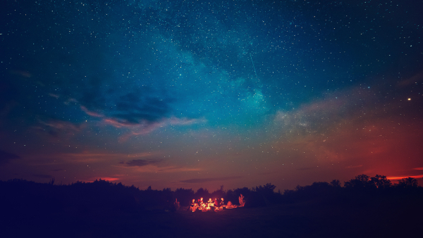 A photo of people near a camp fire under a starry night sky. 