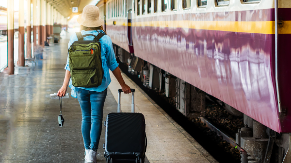 A photo of a woman with a suitcase taking a train. 