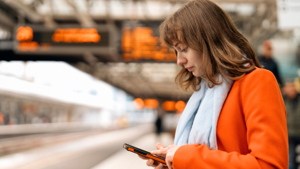 A traveler on their phone waiting for a train. 
