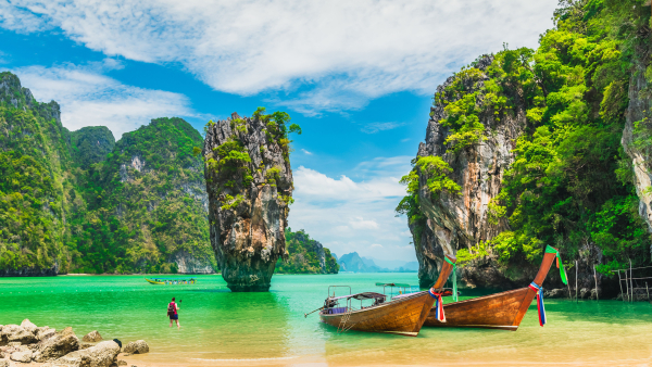 A photo of two boats in front of a beautiful Thailand backdrop.  