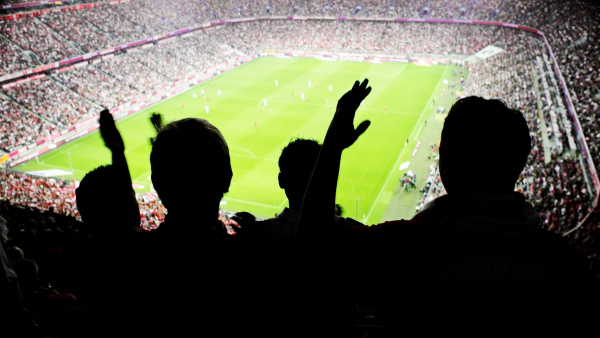 A silhouette of soccer fans watching a game. 