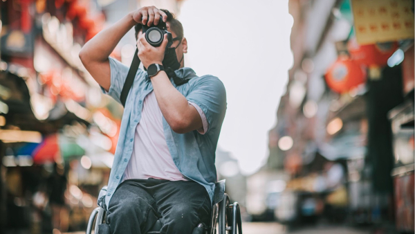 A photo of a man in a wheel chair aiming his camera up to take a photo. 