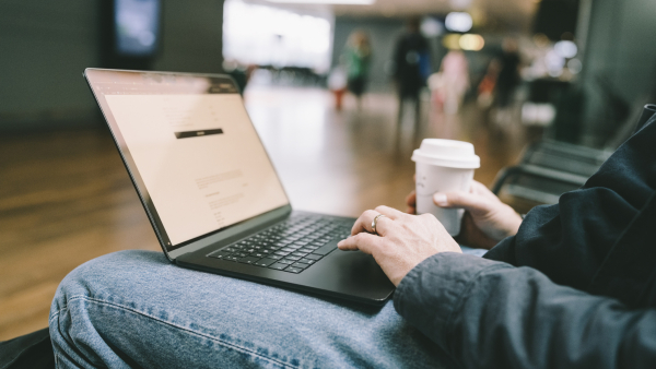 A man typing on his laptop while drinking coffee. 