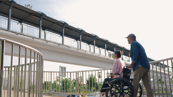 A man pushes a woman in a wheelchair. 