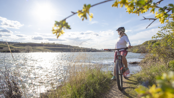A woman biking through a trail alongside a lake in Great Falls, Montana. 