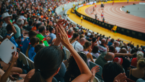 A woman applauding while watching a sporting event. 