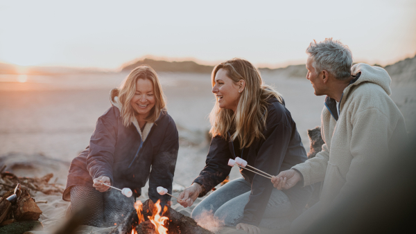 Folks circled around a campfire making smores.