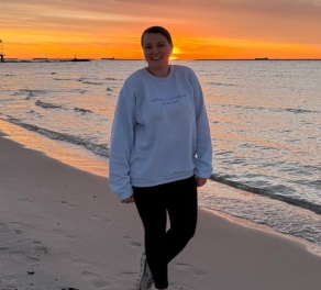 A photo of Emily on the beach while the sun sets. 