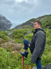 August posing in front of a lush valley. 