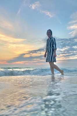 Amanda Pfeil wading in the surf near sunset