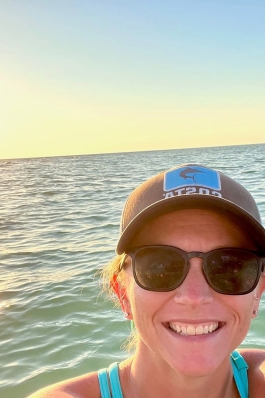 Amanda Steward with ocean and the setting sun behind her