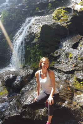 Amy Overbay seated in front of a waterfall
