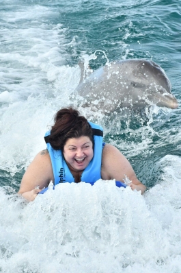Andraya Ticola being towed through the water accompanied by dolphins