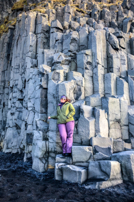 Angela Vaughn leaning against a wall of rectangular-shaped rock pillars