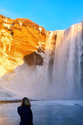 Britt Mattie in front of a large rushing waterfall in Iceland