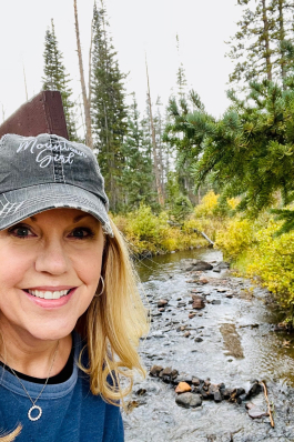 Debbie Johnson in front of a wooded stream in Wyoming