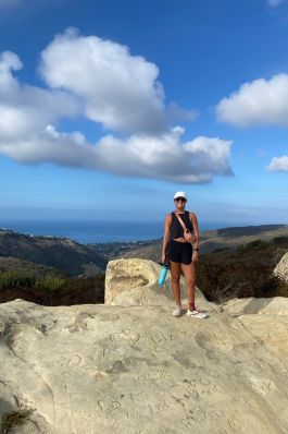 Mary Sergeant standing on a rocky hillside overlooking Laguna Beach, CA