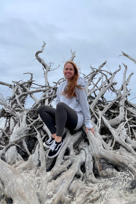 Meghan Alden seated on a pile of driftwood on Jekyll Island, GA
