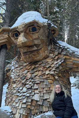 Melissa Bowman in front of a large wooden troll sculpture in Breckenridge, CO