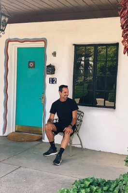 Peter Hosmer in front of a colorful doorway with dried chilis hanging from the porch in Santa Fe