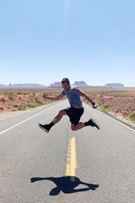 Peter Hosmer jumping in the air on an empty desert road in Utah