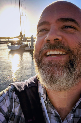 CA Clark in front of a boat and water