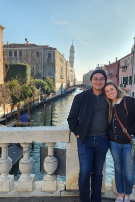 A photo of Holly and her husband on a bridge over a river. 