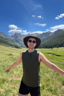 A photo of Joe in Colorado in a field surrounded by mountains. 