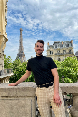 A photo of Joe in Paris with the Eifel tower in the background.